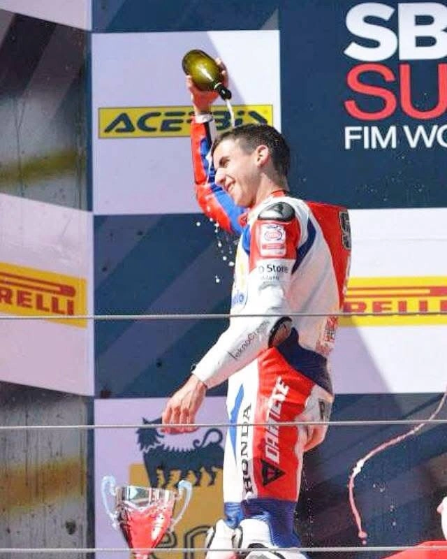 Emanuele festeggia sul podio alzando la bottiglia